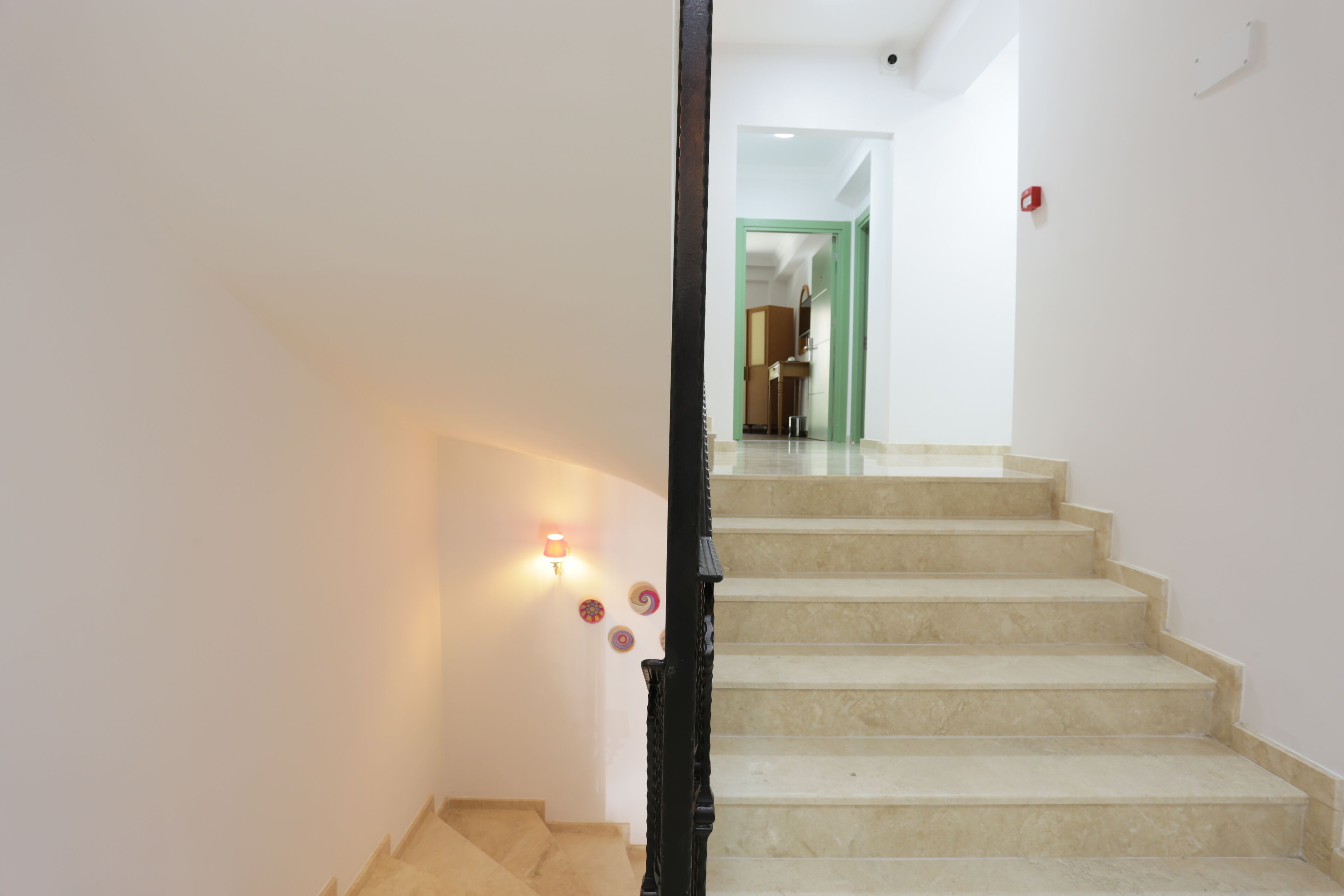 A staircase with beige steps and a black handrail, leading to a room with a green door.