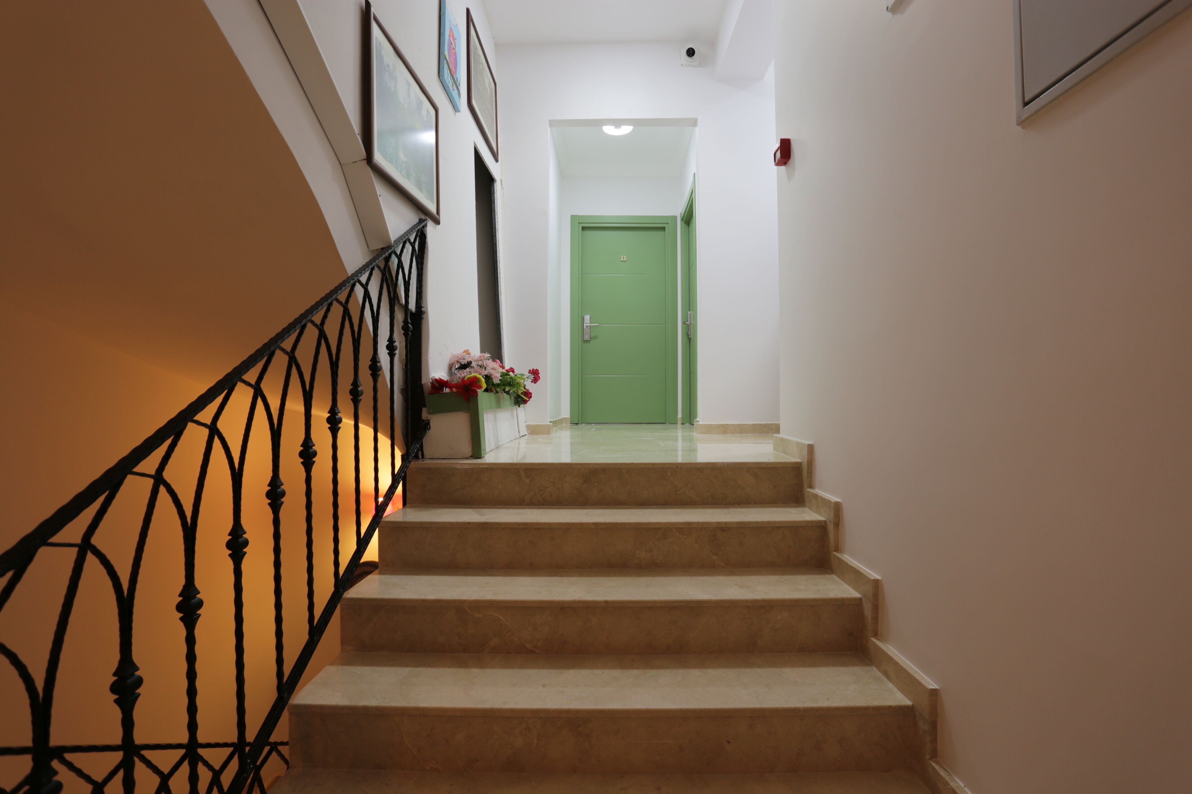 Una escalera que lleva a una habitación, con una puerta verde en la parte superior.
