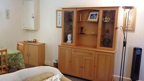 A bedroom with a bed, wooden wardrobe, and a small table with chairs.