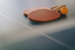 Dos paletas de tenis de mesa y una pelota sobre una mesa azul.