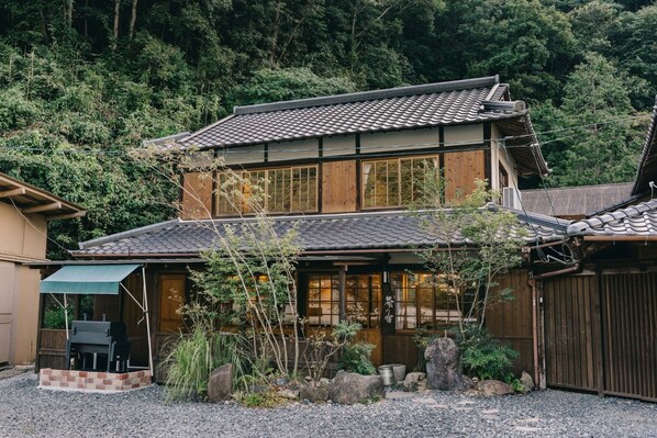 Un edificio de estilo japonés tradicional con tejado de tejas, fachada de madera y un espacio de estar al aire libre cubierto.