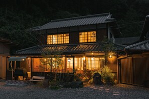Una casa japonesa tradicional con tejado de tejas, ventanas grandes y un porche cubierto.