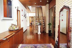 Uma escada de madeira leva a um patamar com corrimão decorativo, um pilar branco e um espelho à direita.