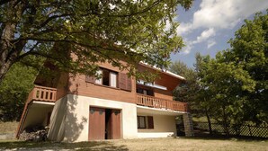 Une maison à deux étages avec un balcon, une porte d’entrée et un garage visible.