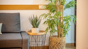 Un salon moderne avec un canapé gris, une table basse ronde et une grande plante en bambou dans un panier tressé.
