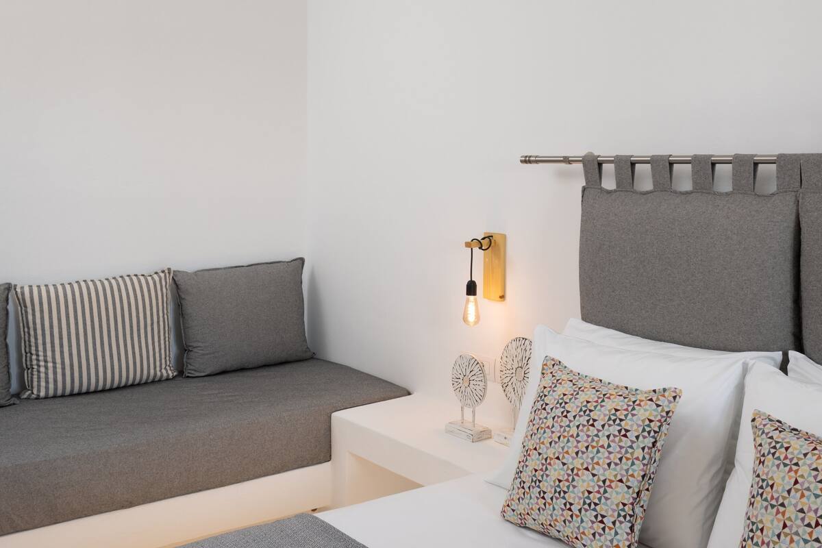 A modern bedroom with a bed, bedside table, lamp, and a hanging light fixture.