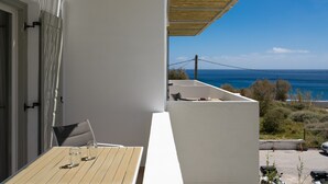 A balcony with a table, chairs, and a view of the sea. - Sunray Lodgings (Santorini)