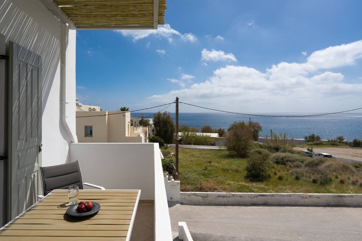 A balcony with a table, a chair, and a plate with fruit.