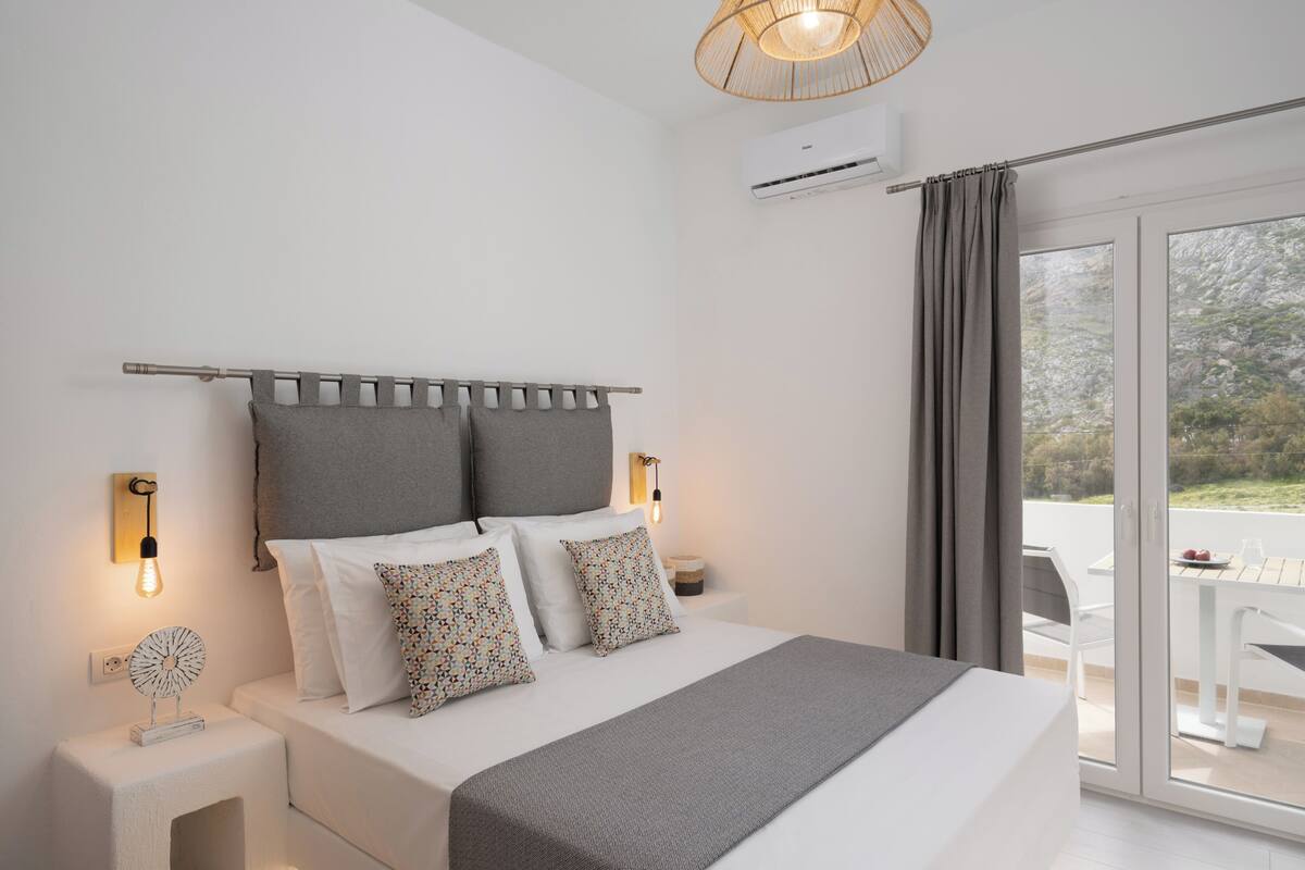 A modern bedroom with a bed, bedside lamps, and a view through a glass door.
