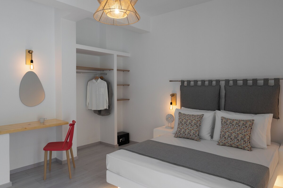 A bedroom with a bed, bedside tables, a chair, a desk, and a wardrobe.