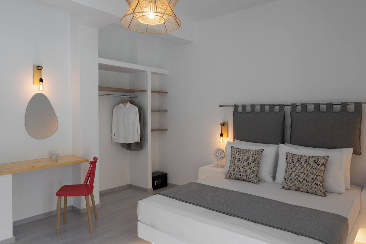 A bedroom with a bed, bedside tables, a chair, a desk, and a wardrobe.