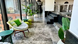 Un interior moderno con zona de estar, plantas en macetas y vistas de la ciudad a través de amplias ventanas.
