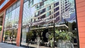 Un edificio moderno con amplios ventanales y un cartel que dice "Visita nuestro departamento".