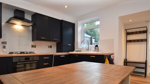 Una cocina moderna con armarios oscuros, una mesa de madera y un ventanal que proporciona luz natural.
