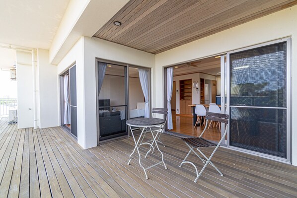 A covered outdoor area with a wooden deck, a small table, and chairs.