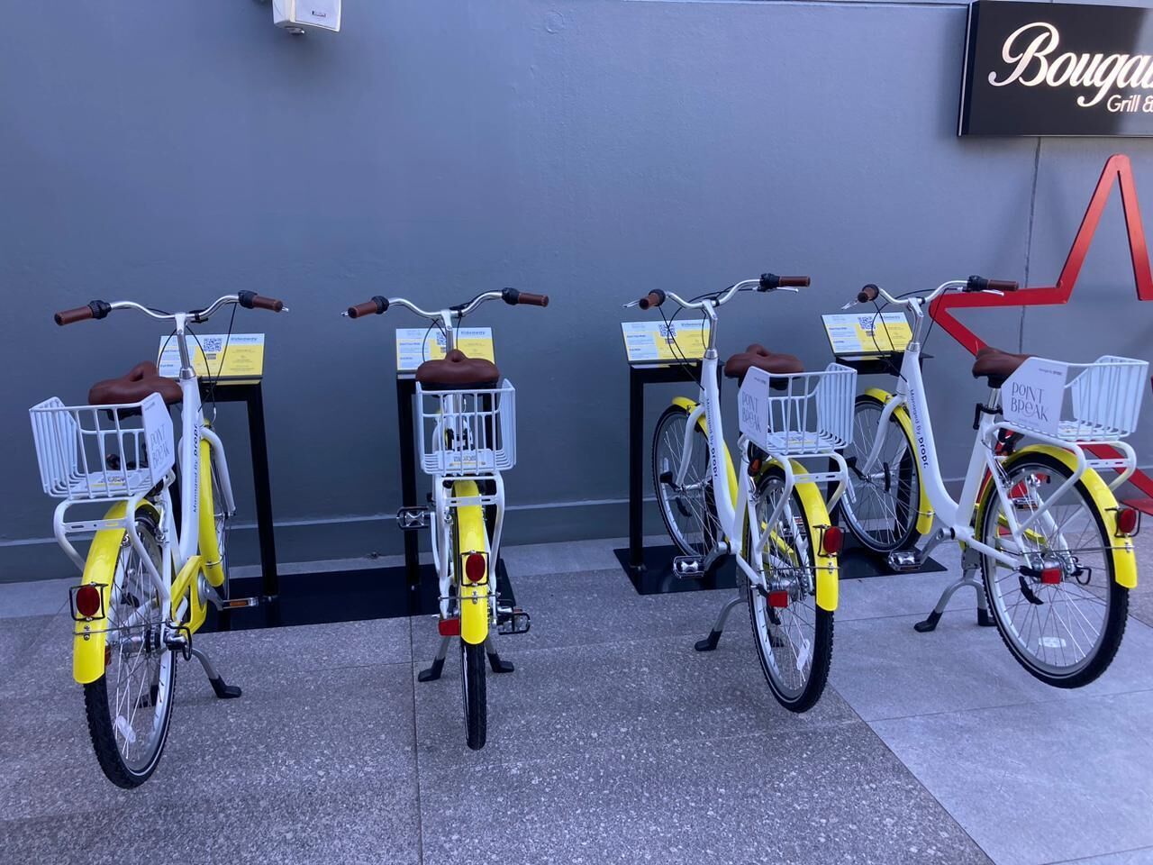 Three bicycles parked in front of a building with a sign that reads "Bouganville Grill & Bar".