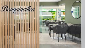 A modern interior with a wooden partition displaying the name "Bougainvillea Grill & Lounge". - Point Break | Serviced Studio | Mountain Views (Cape Town)