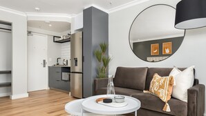 A modern living room with a brown sofa, a white coffee table, and a round mirror on the wall. - Point Break | Sleek Studio | Mountain Views (Cape Town)