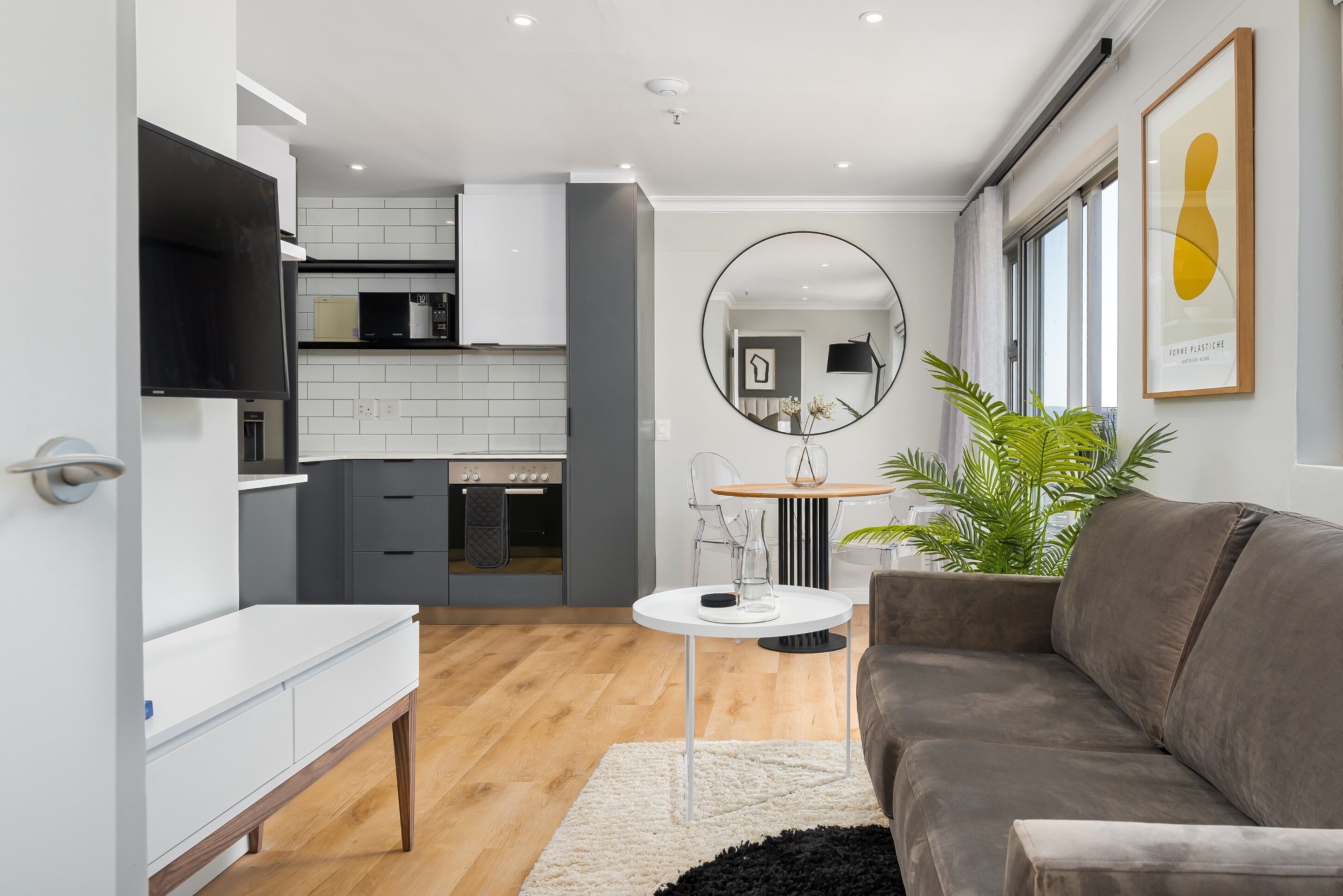 Un salon moderne avec un canapé gris, une table basse ronde et un tapis blanc.