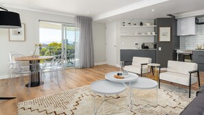 A modern living room with a dining area, a kitchen, and a balcony with a city view. - Point Break | Luxe 1 Bedroom | Balcony | Netflix (Cape Town)