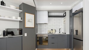 A modern kitchen with grey cabinets, white tiles, and stainless steel appliances. - Point Break | Luxe 1 Bedroom | Balcony | Netflix (Cape Town)
