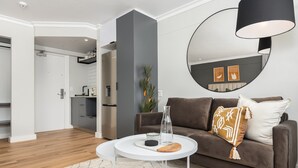 A modern living room with a brown sofa, a white coffee table, and a large mirror on the wall.
