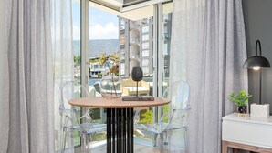 A modern room with a round table, clear chairs, a lamp, and a view of a cityscape through large windows.