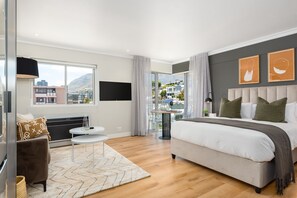 A modern hotel room with a large bed, a sofa, a small table, and a TV.