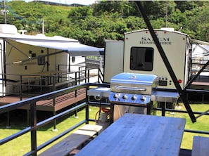 Un área de camping con una parrilla y una caravana Hemispheria.