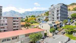 Zona residencial con edificios modernos, una casa de techo rojo y montañas al fondo.