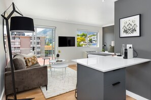 Un salon moderne avec un canapé, une table basse et une grande fenêtre donnant sur la ville.