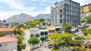 A multi-story residential building with balconies, surrounded by greenery and other houses. - Point Break | Table Mountain Views | Pool (Cape Town)