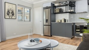 A modern kitchen with grey cabinets, a stainless steel refrigerator, and a built-in oven. - Point Break | Table Mountain Views | Pool (Cape Town)
