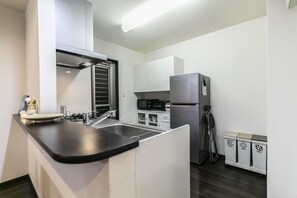 A compact kitchen with a black countertop, stainless steel appliances, and a microwave.