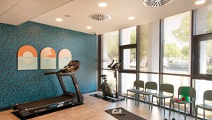 Una palestra moderna con attrezzature per esercizi, pavimento in legno e ampie finestre.