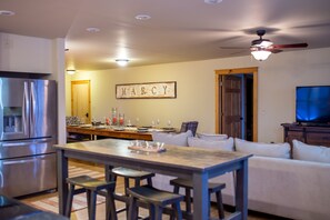 A modern kitchen with a built-in refrigerator, a dining area with a bar stool, and a living room with a television.