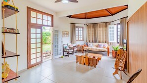 A spacious living area with a sofa set, wooden coffee table, and a ceiling fan.