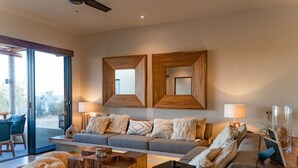 A modern living room with a grey sofa, wooden coffee table, and a glass door leading to an outdoor area. - Ocean View Penthouse with Rooftop Terrace (Huatulco)