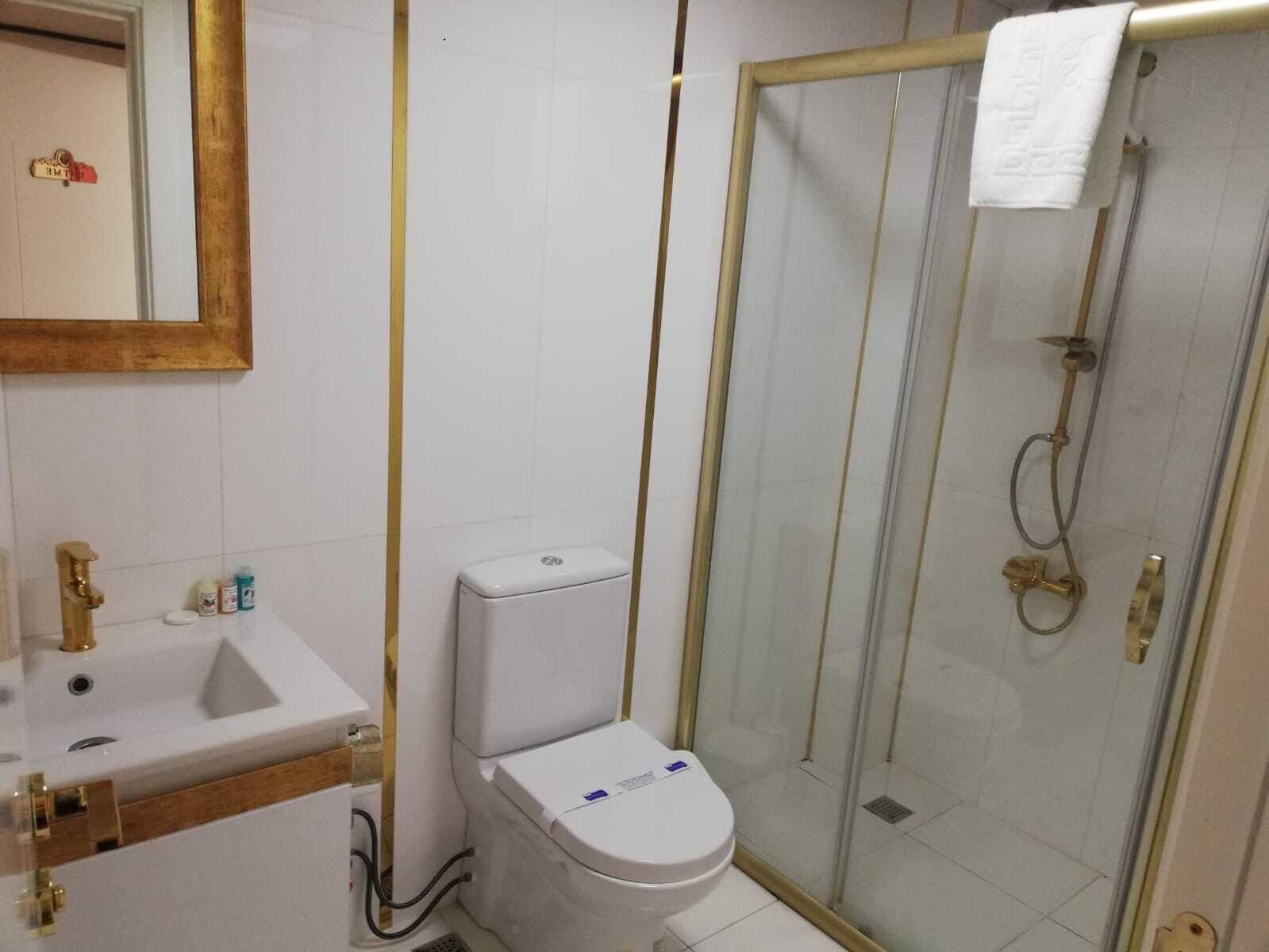 Une salle de bain comprenant des toilettes, un lavabo et une douche fermée par des parois en verre.