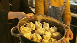 Cuina amb dues persones preparant dumplings.