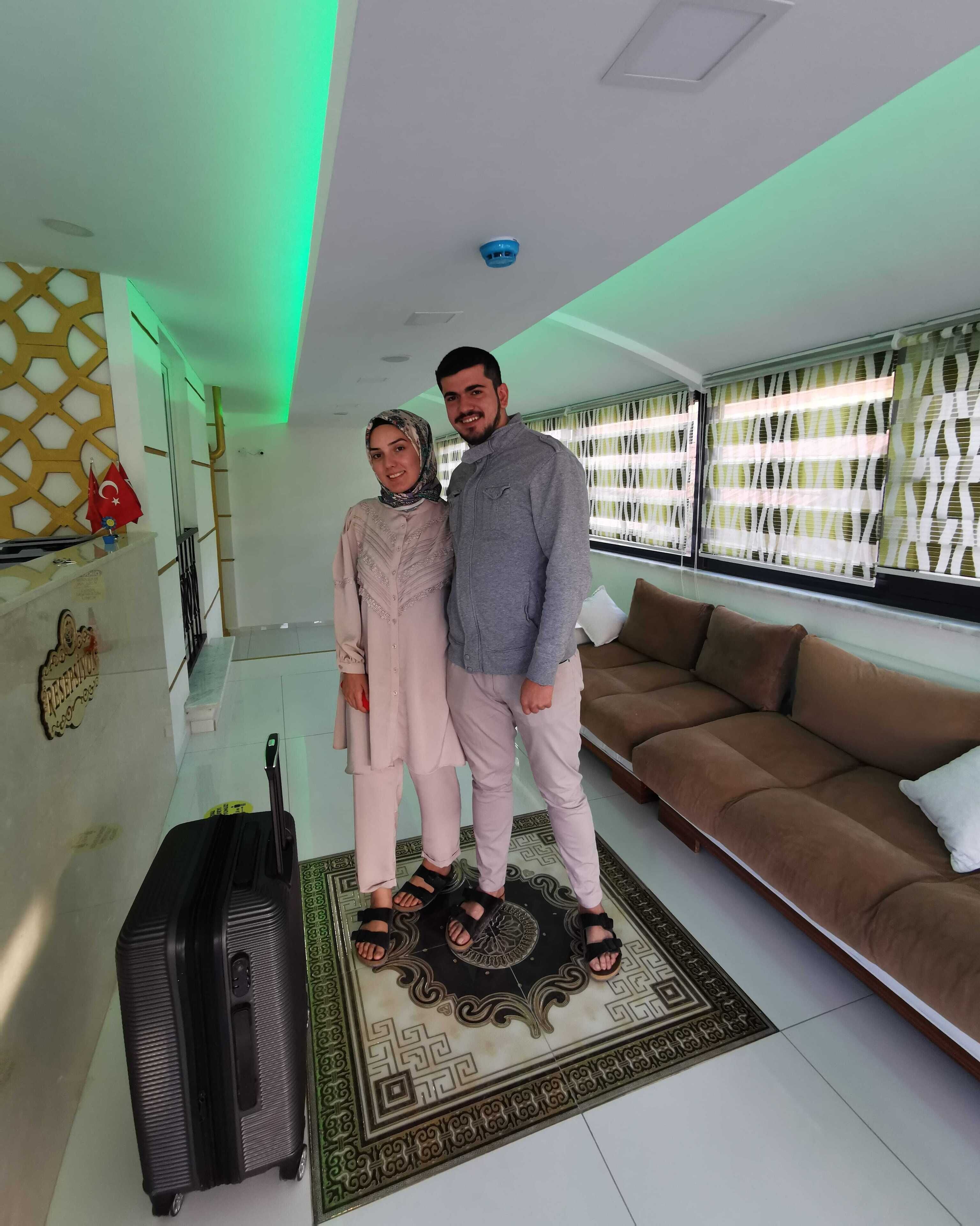 A modern living room with a brown sofa, a patterned rug, and a black suitcase.