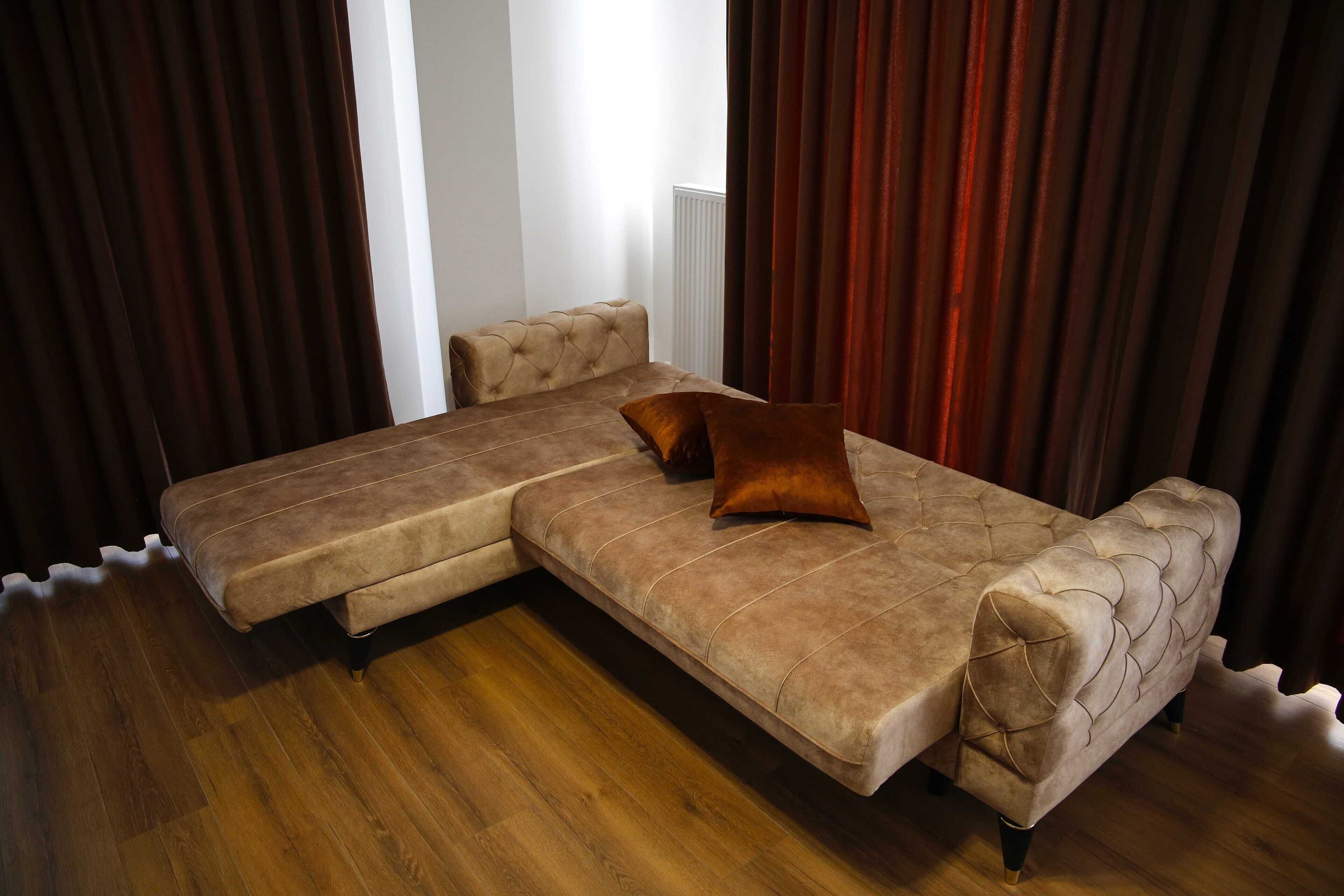 A sectional sofa with a tufted design, a matching ottoman, and a single brown cushion.