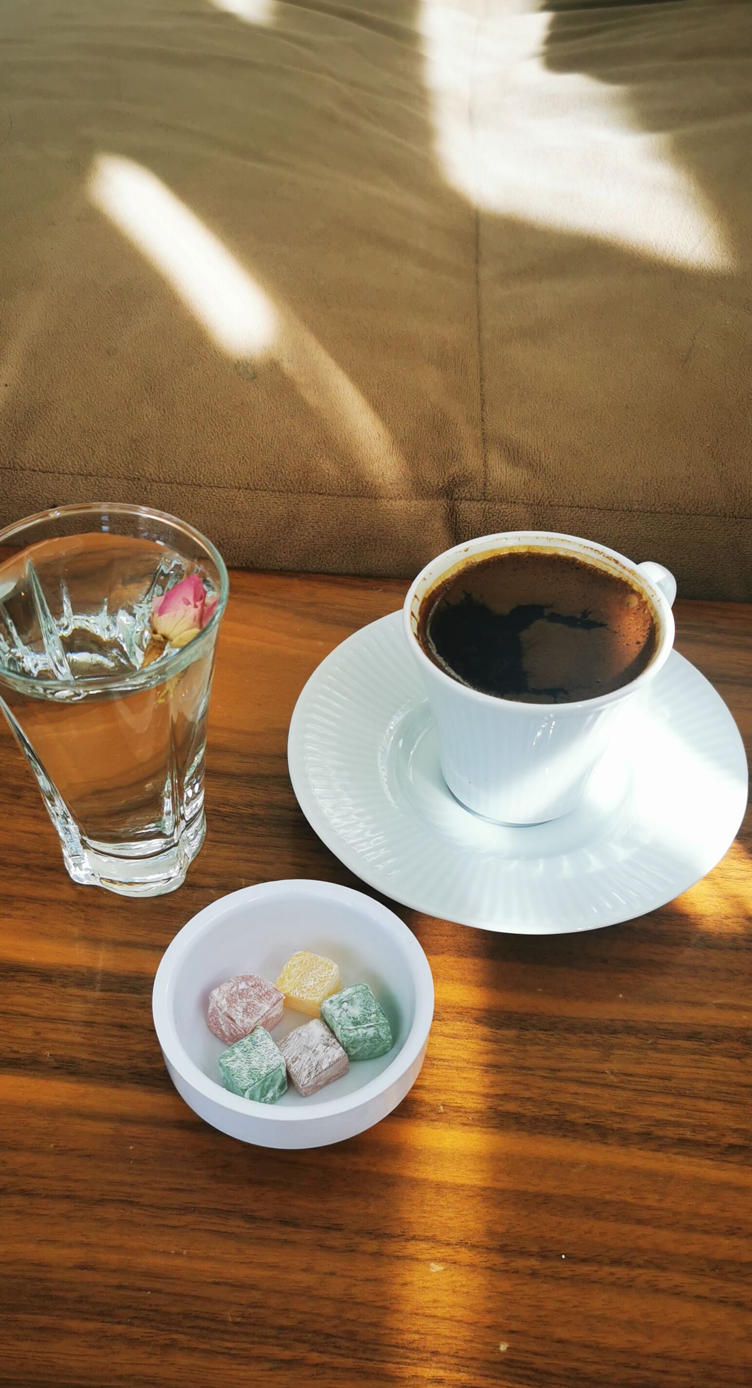 A table with a cup of coffee, a glass of water, and a bowl of colorful candies.