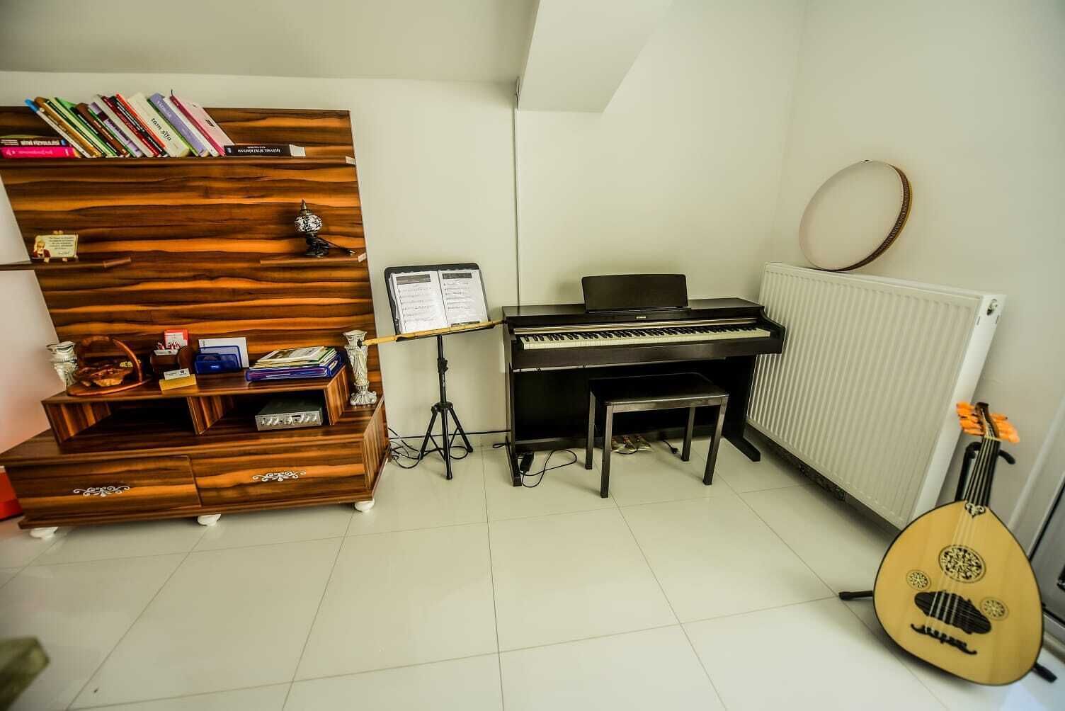Una stanza con un pianoforte, un leggio, una libreria e un mandolino.