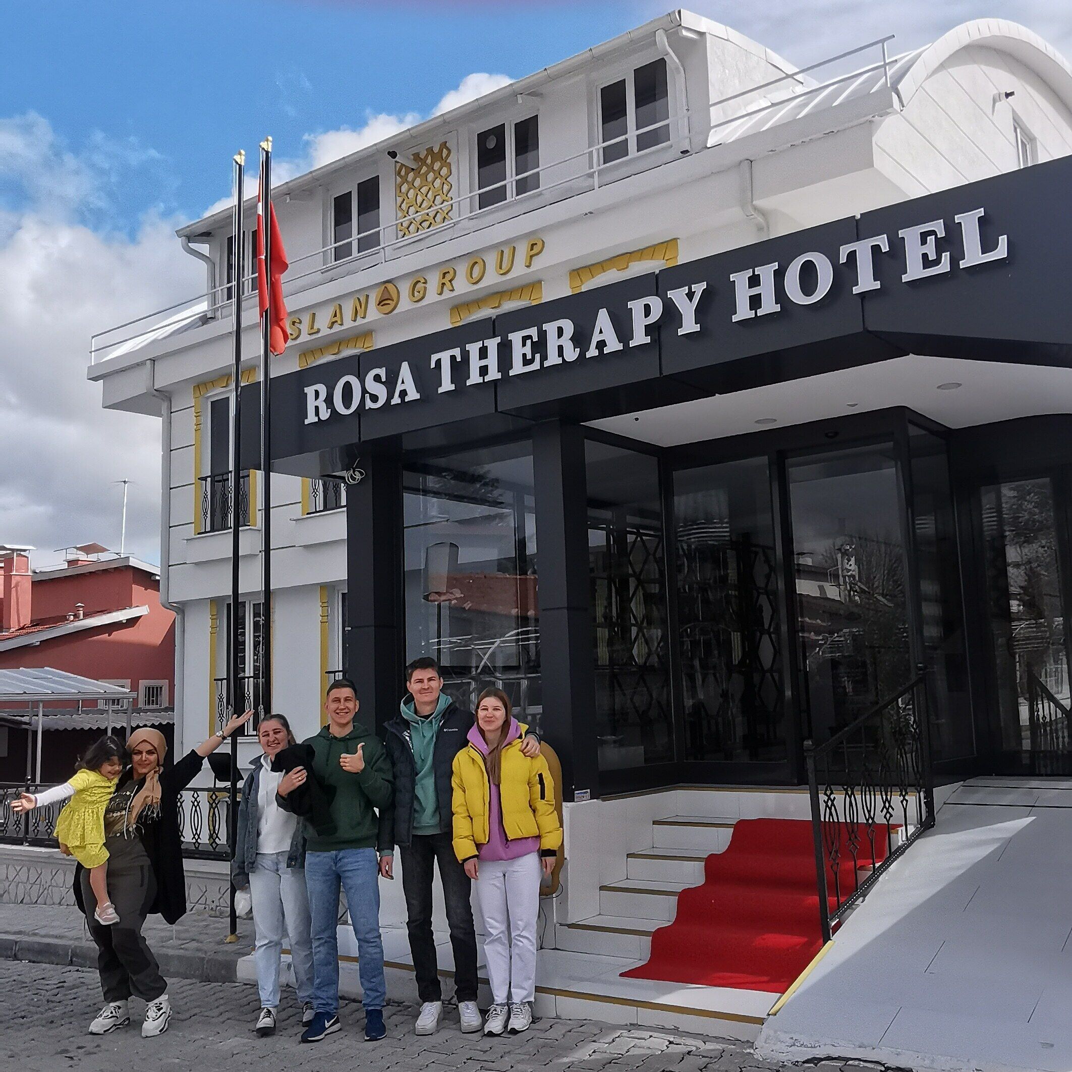 Un grupo de personas frente a un edificio con un letrero que dice "Rosa Therapy Hotel".