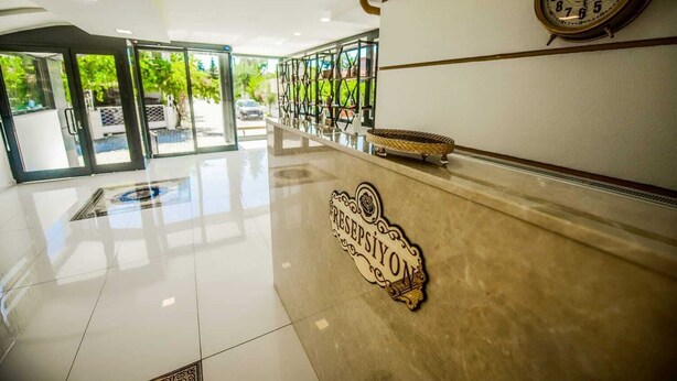 Zona d'entrada d'un hotel amb un sòl polit, un rellotge a la paret i un emblema decoratiu.
