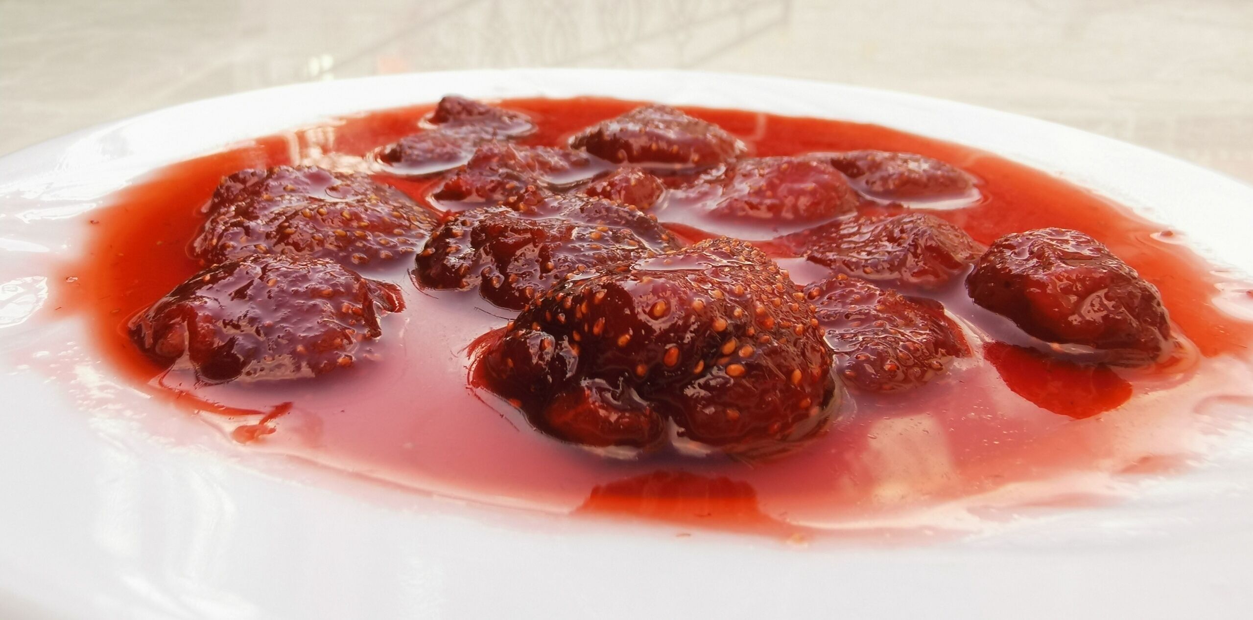 A plate of dried fruits in a red syrup.