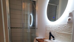 Een badkamer met douche, toilet en wastafel.