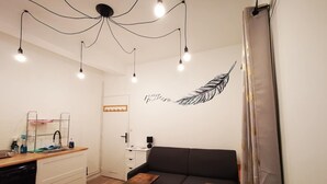 Een moderne woonkamer met een zwarte bank, een houten salontafel en een wandlamp.