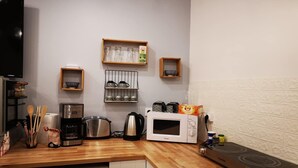 Een compacte keuken met een vaatwasser, koffiezetapparaat, waterkoker, magnetron en gasfornuis.